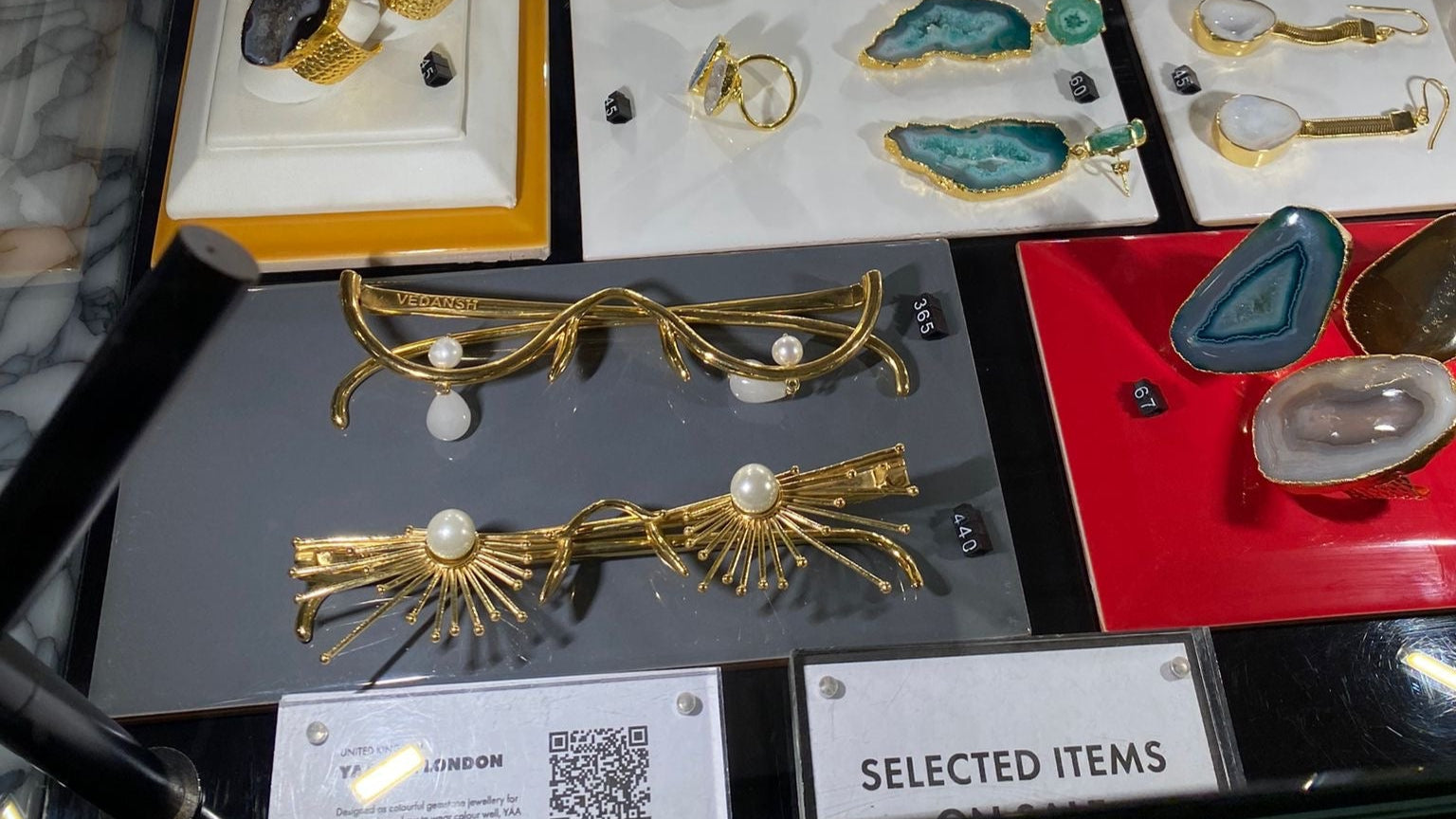 Display of jewelry items including rings and brooches on a glass table.