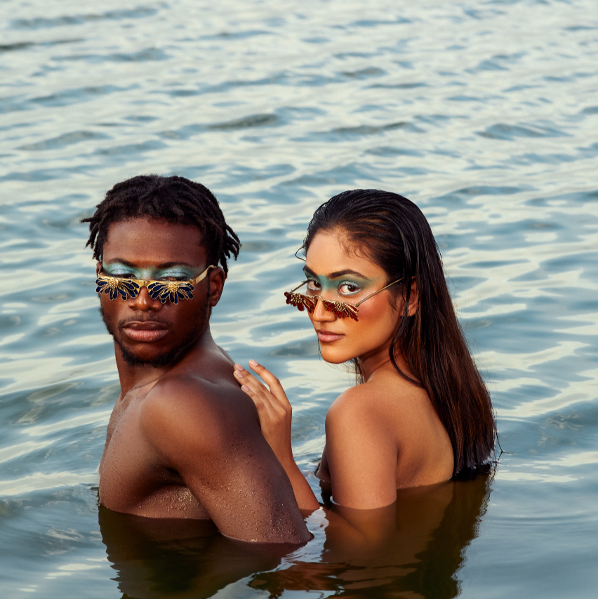 Two people standing in water wearing sunglasses